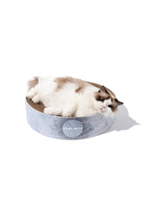 ragdoll-cat-comfortably-lying-on-side-in-kamamuta-cat-scratcher-board-bed-on-white-background
